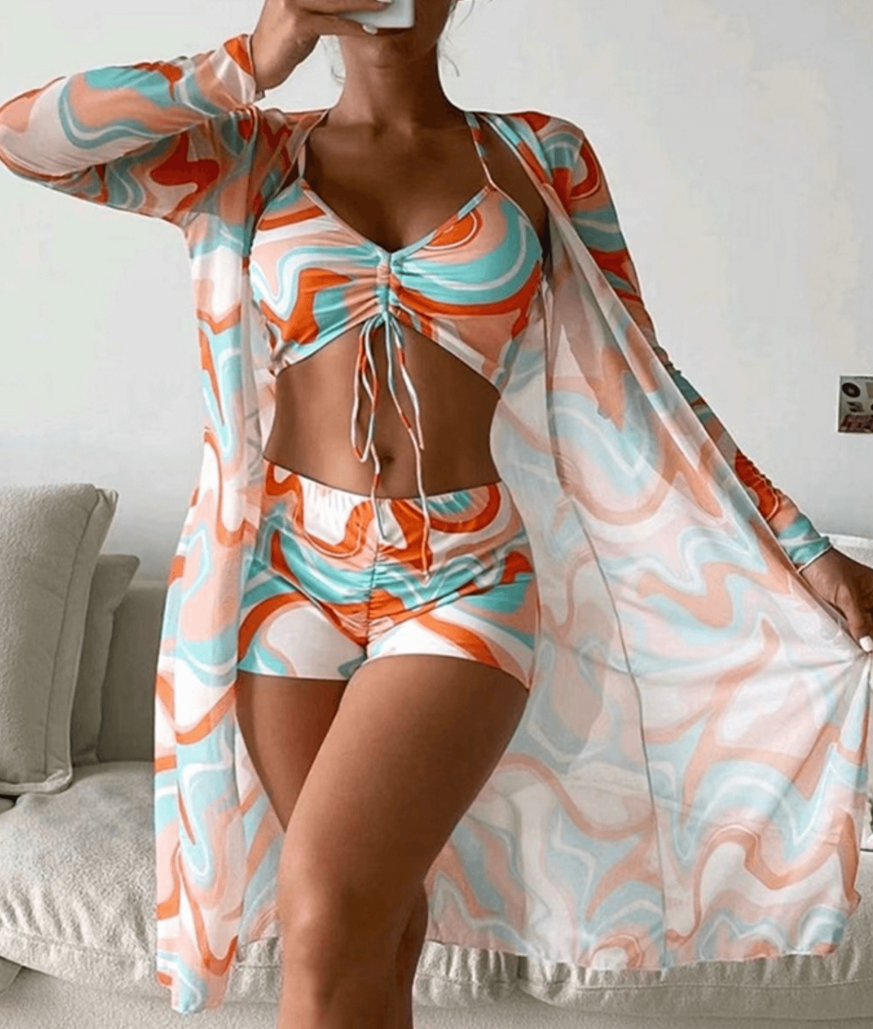 Donna in abbigliamento estivo colorato con motivo astratto, composto da top, shorts e kimono coordinati. Moda femminile, abbigliamento casual estivo.