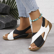 Sandali donna bianchi e neri con zeppa, indossati con jeans chiari. Design moderno, comodi per l'estate. Accessorio cavigliera turchese.