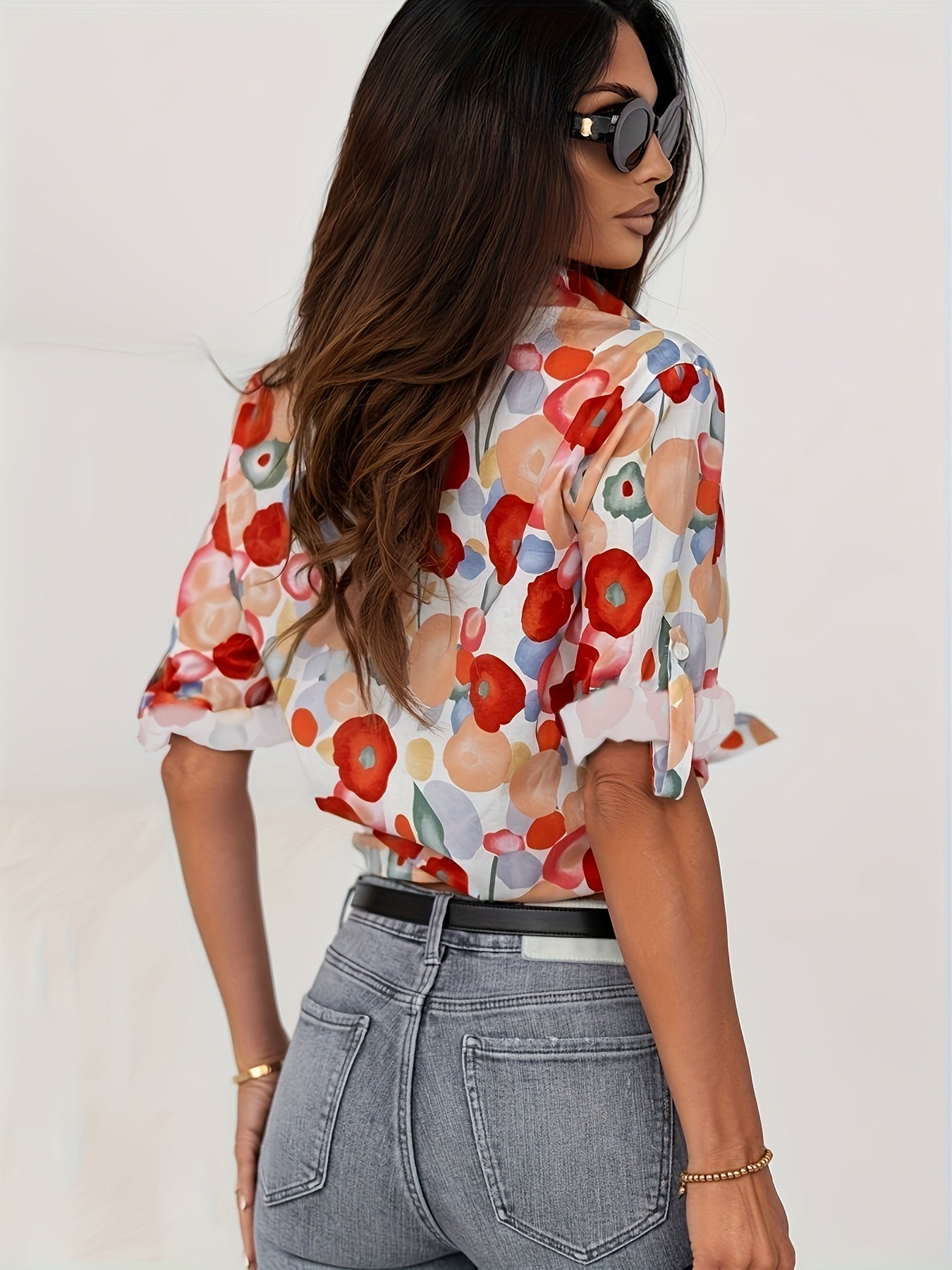 Donna con camicia a fiori colorati, jeans aderenti e occhiali da sole. Moda femminile, abbigliamento casual elegante, stile estivo.