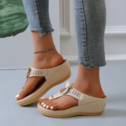 Sandali beige con zeppa, cinturino regolabile e dettagli traforati, indossati con jeans aderenti. Scarpe estive eleganti e comode per donna.