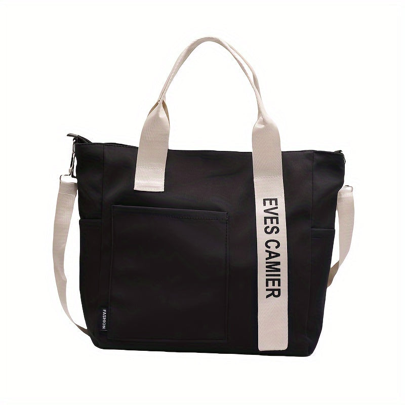 Borsa tote nera con manici bianchi, tasca frontale e scritta "EYES CAMIER". Design moderno, ideale per shopping e uso quotidiano.