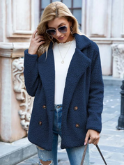 Donna con cappotto blu in lana bouclé, occhiali da sole, maglia bianca e jeans strappati. Moda autunnale, stile casual chic, abbigliamento femminile.
