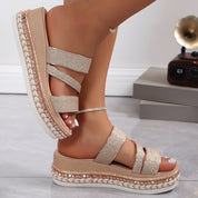 Sandali platform donna glitter beige, cinturini incrociati, suola spessa intrecciata, moda estiva, calzature eleganti, pavimento in marmo.