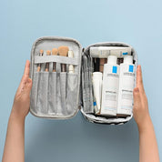 Astuccio da viaggio aperto con prodotti La Roche-Posay Effaclar e pennelli trucco su sfondo azzurro. Organizzatore cosmetici compatto e pratico.