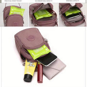 Borsa a tracolla rosa con tasche multiple, contenente smartphone, portafoglio, rossetto e salviette. Design compatto e pratico per l'uso quotidiano.