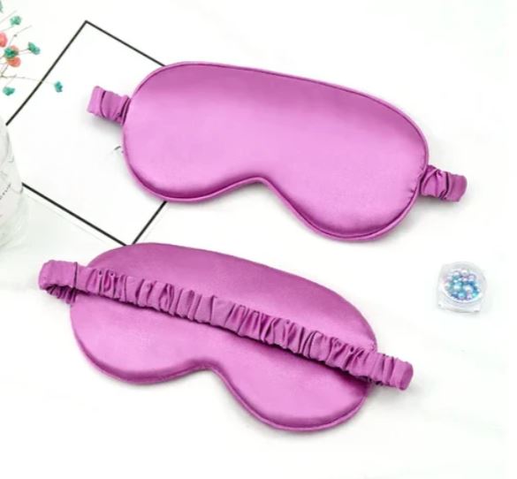 Due mascherine per dormire in seta viola su sfondo bianco, ideali per il relax e il sonno. Accessori per il benessere e il riposo notturno.