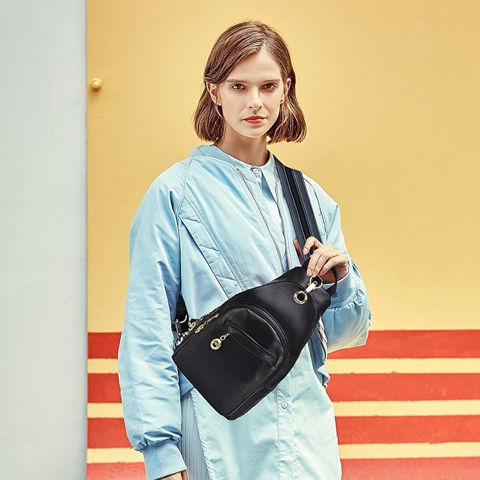 Donna con giacca azzurra indossa borsa a tracolla nera elegante, sfondo giallo e rosso. Moda femminile, accessori trendy, stile urbano.