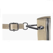 Cinturino in pelle beige con fibbia e moschettone in metallo argentato, dettaglio di borsa elegante, accessorio moda donna.