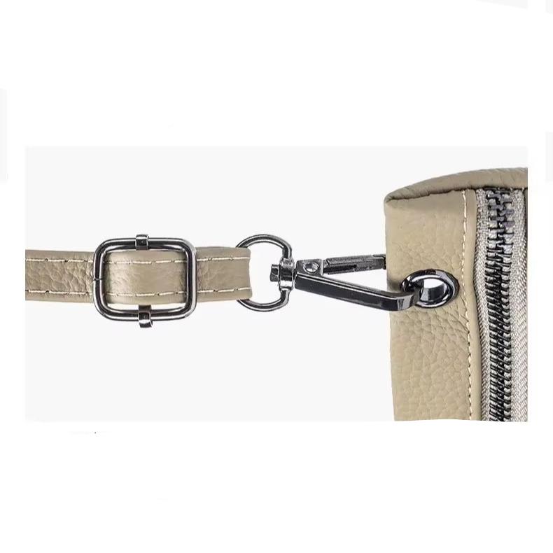 Cinturino in pelle beige con fibbia e moschettone in metallo argentato, dettaglio di borsa elegante, accessorio moda donna.