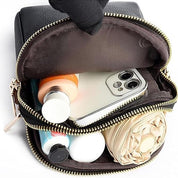 Custodia nera aperta con smartphone, flaconi cosmetici e accessori. Organizzatore compatto da viaggio, ideale per trucco e gadget.
