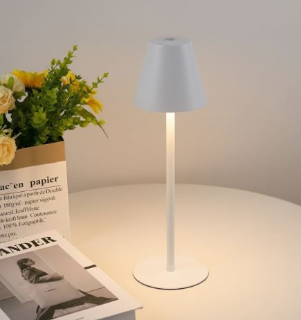 Lampada da tavolo moderna bianca su tavolo rotondo, accesa, con fiori gialli e riviste. Design minimalista, illuminazione interna elegante.