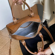 Borsa a mano in pelle marrone con cerniera aperta, manici robusti e tracolla regolabile. Design elegante, ideale per moda donna e accessori.