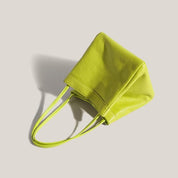 Borsa a mano in pelle verde lime su sfondo beige, design moderno ed elegante, accessorio moda donna, perfetta per look estivi e casual.