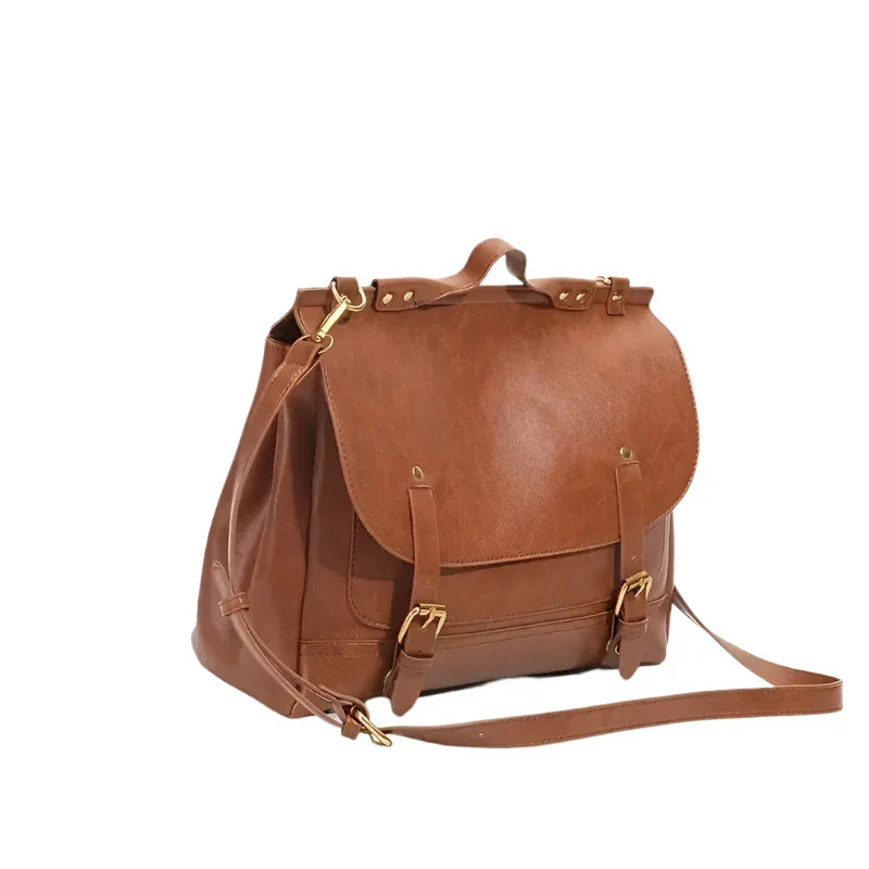 Zaino in pelle marrone con chiusura a fibbia, manico superiore e tracolla regolabile. Design elegante e spazioso, ideale per l'uso quotidiano.