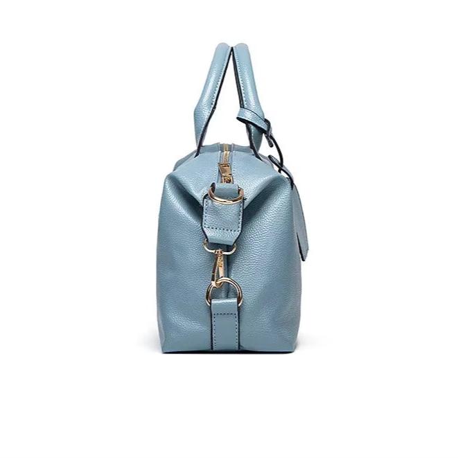 Borsa a mano in pelle blu, vista laterale, con manici e dettagli metallici dorati. Elegante accessorio moda donna.