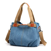 Borsa a tracolla in tela blu con manici beige, dettagli in pelle marrone, tasche laterali e tracolla regolabile. Elegante e pratica per ogni occasione.