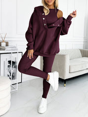 Donna in tuta sportiva bordeaux con spalla scoperta, abbinata a sneakers bianche. Outfit casual chic per moda autunnale.