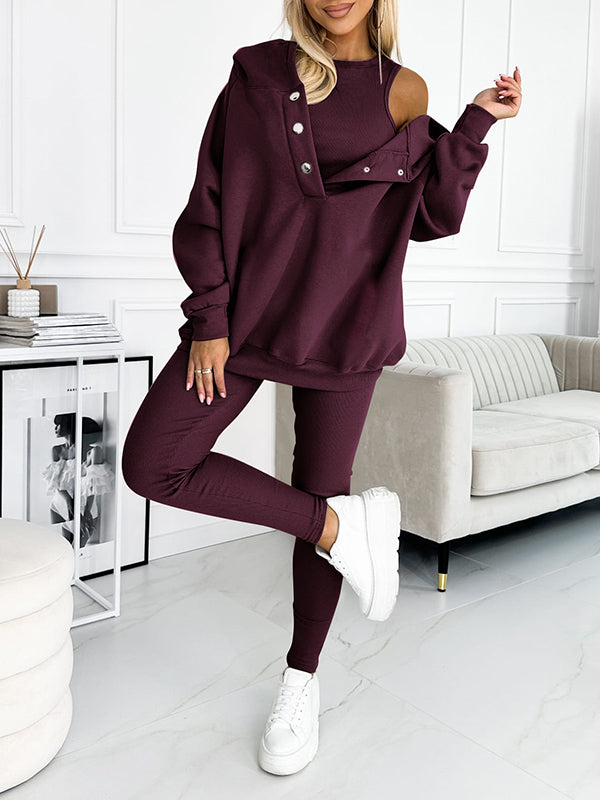 Donna in tuta sportiva bordeaux con spalla scoperta, abbinata a sneakers bianche. Outfit casual chic per moda autunnale.