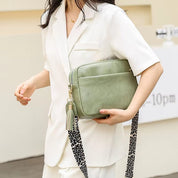 Donna con borsa a tracolla verde in pelle, design elegante, con nappina e tracolla leopardata. Moda femminile, accessori di tendenza.