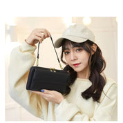 Donna con cappello beige tiene una borsa a tracolla nera elegante. Moda femminile, accessori, stile casual. Sfondo chiaro e luminoso.