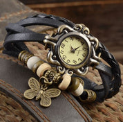 Orologio vintage con cinturino in pelle intrecciata nera, quadrante antico e ciondolo a farfalla. Accessorio moda retrò elegante.