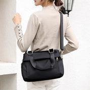 Donna con borsa a tracolla nera elegante, design moderno, chiusura con zip, ideale per lavoro e tempo libero. Accessorio moda femminile versatile.