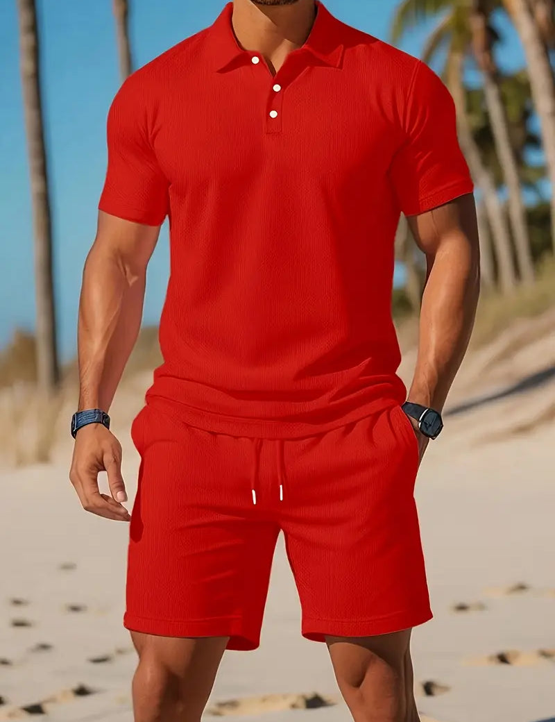 Uomo in completo estivo rosso su spiaggia, indossa polo e pantaloncini coordinati. Moda mare, abbigliamento casual estivo, stile vacanza.