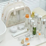 Set di cosmetici di lusso su tavolo bianco con borsa trasparente. Include creme, sieri, lozioni e flaconi eleganti. Skincare di alta gamma.