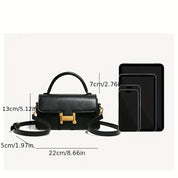 Borsa a tracolla nera in pelle con chiusura dorata, dimensioni 22x13x7 cm, accanto a smartphone e tablet per confronto grandezza. Accessorio moda elegante.