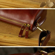 Borsa in pelle marrone con cerniera dorata e dettagli in metallo, design elegante e resistente, ideale per moda e accessori di lusso.