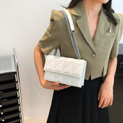 Donna con borsa a tracolla bianca trapuntata, giacca beige e gonna nera. Accessorio moda elegante, perfetto per look casual e formali.