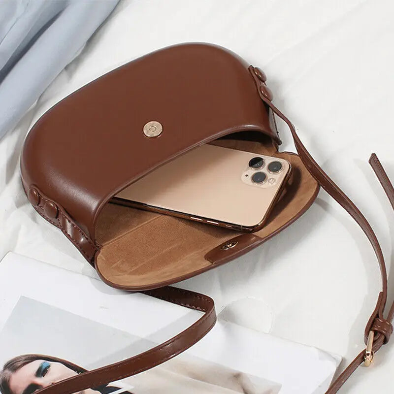 Borsa a tracolla in pelle marrone con smartphone all'interno, design elegante, accessorio moda donna, perfetta per uso quotidiano e serate.