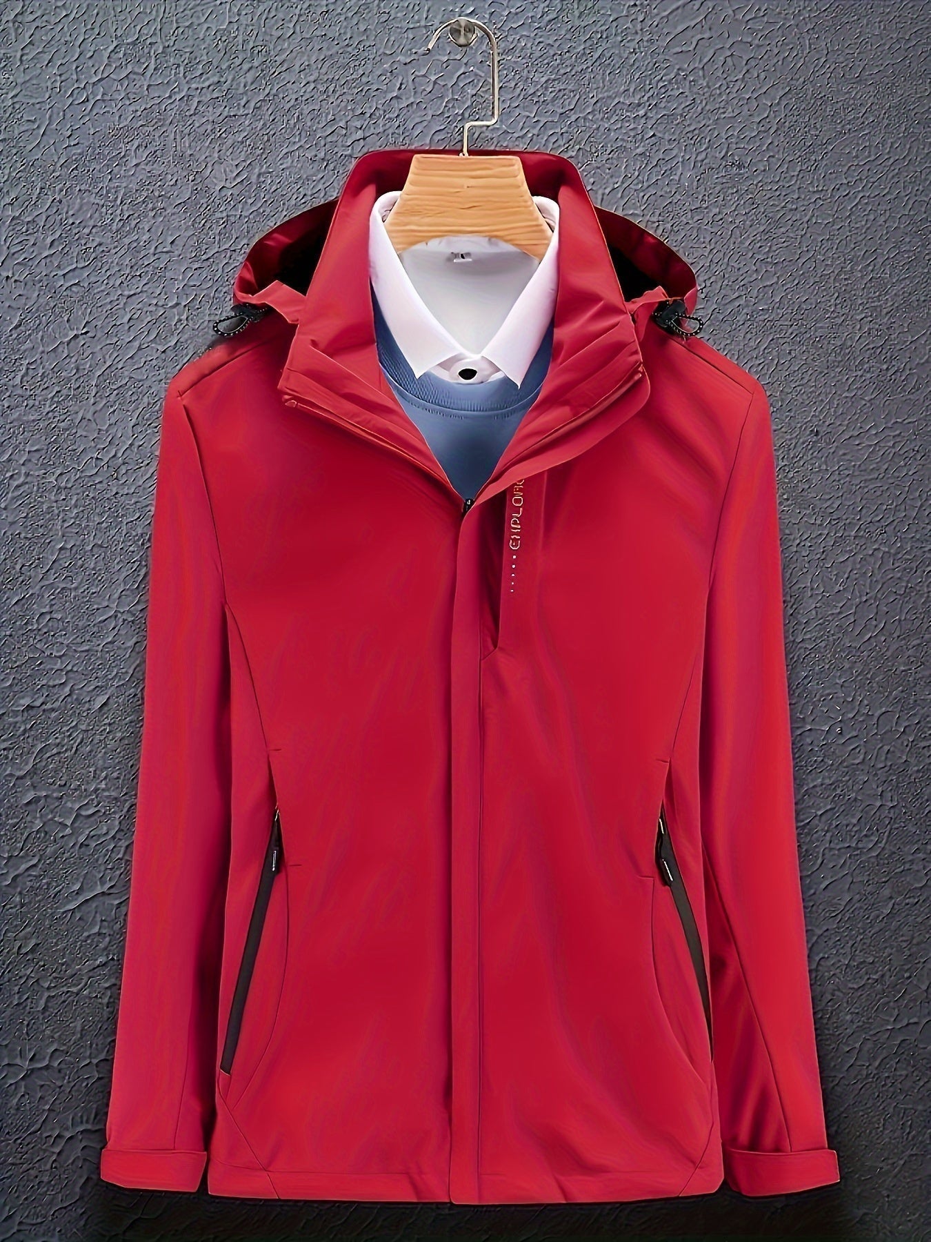 Giacca rossa impermeabile con cappuccio, appesa su gruccia, su sfondo grigio. Ideale per outdoor, moda uomo, abbigliamento casual.