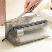 Borsa trasparente da viaggio con cerniera, contenente flaconi di cosmetici. Design compatto, ideale per organizzare prodotti di bellezza.