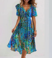 Abito estivo donna, fantasia astratta blu e verde, scollo a V, maniche corte, lunghezza media, tessuto leggero, moda casual elegante.