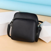 Borsa a tracolla in pelle nera su sfondo colorato, design elegante e moderno, ideale per uomo e donna. Accessorio moda versatile e di tendenza.