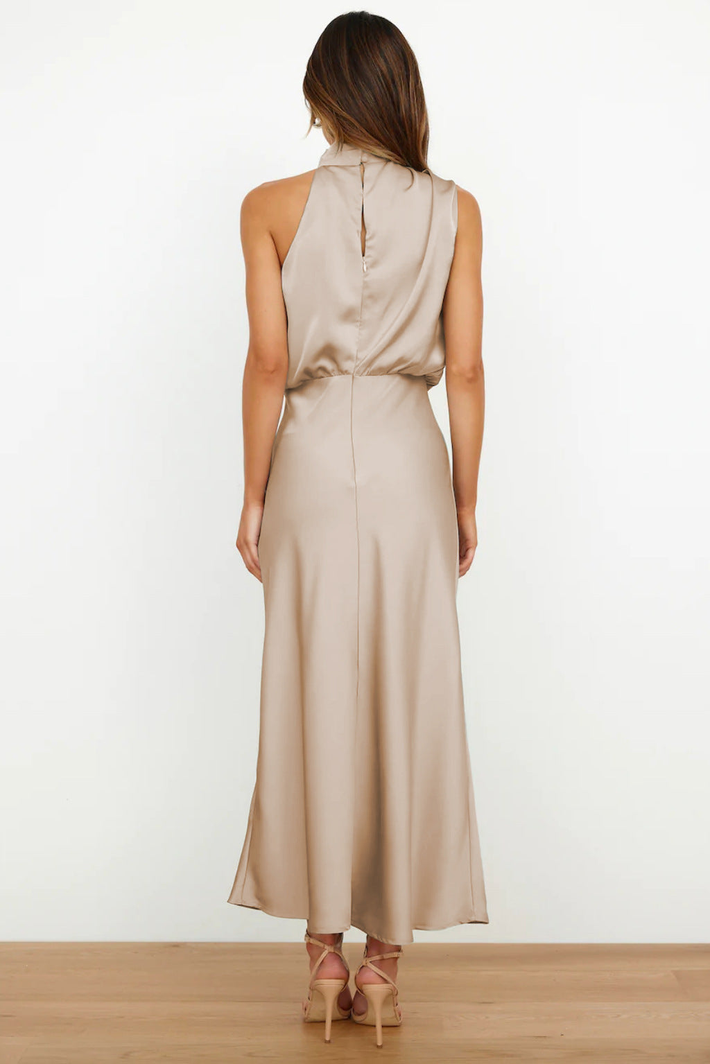 Abito lungo elegante in raso beige, senza maniche, con schiena scoperta. Perfetto per eventi formali e serate speciali.
