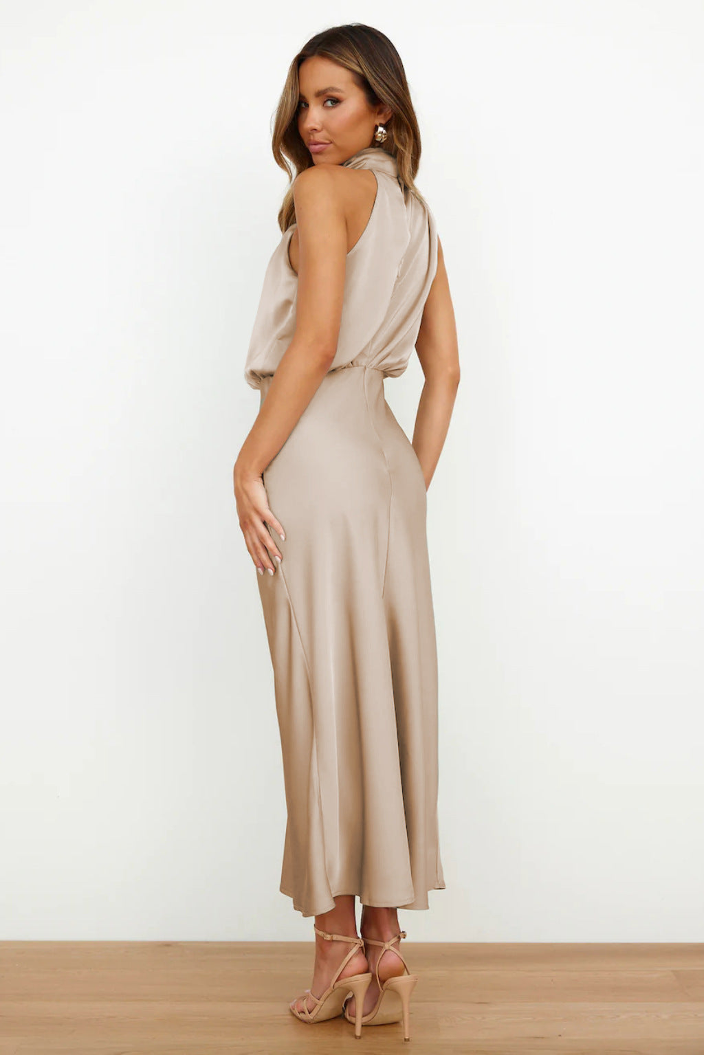 Abito lungo elegante in raso beige, senza maniche, con scollo a V e schiena scoperta. Perfetto per eventi formali e serate speciali.