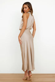 Abito lungo elegante in raso beige, senza maniche, con scollo a V e schiena scoperta. Perfetto per eventi formali e serate speciali.