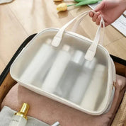 Borsa da viaggio trasparente con manici bianchi, ideale per cosmetici e articoli da toeletta. Perfetta per organizzare il bagaglio a mano.