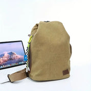 Zaino beige in tessuto con tasca laterale, accanto a un laptop aperto. Design moderno, ideale per scuola o lavoro. Accessori alla moda.