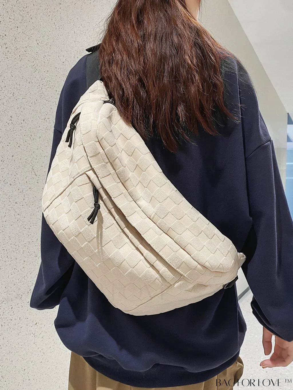 Donna con borsa a tracolla beige intrecciata, indossa maglia blu scuro. Accessorio moda casual, ideale per shopping e viaggi.