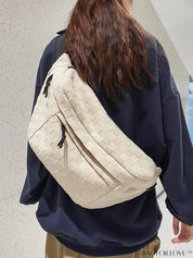 Donna con borsa a tracolla beige intrecciata, indossa maglia blu scuro. Accessorio moda casual, ideale per shopping e viaggi.