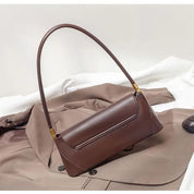 Borsa a spalla in pelle marrone su cappotto beige, design elegante e minimalista, ideale per moda autunno, accessorio donna di tendenza.