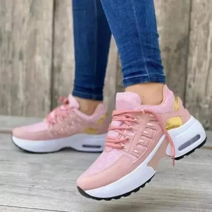 Scarpe da ginnastica rosa da donna con suola bianca e dettagli dorati, indossate con jeans aderenti. Sneakers moda casual, comfort e stile.