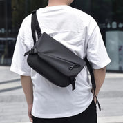 Zaino a tracolla nero impermeabile indossato da uomo, design moderno e minimalista, ideale per viaggi e uso quotidiano.