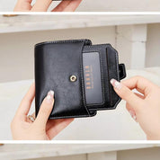 Portafoglio nero in pelle con chiusura a bottone, tasca trasparente per carte. Design elegante, compatto, ideale per donna. Accessorio moda essenziale.