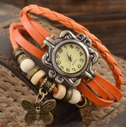 Orologio vintage con cinturino intrecciato in pelle arancione, quadrante antico e ciondolo a farfalla. Design retrò elegante e unico.