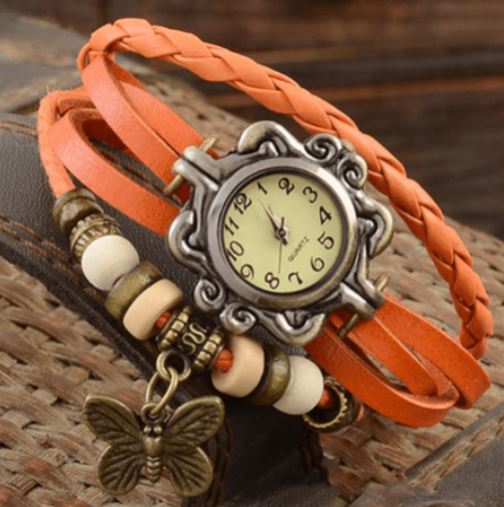 Orologio vintage con cinturino intrecciato in pelle arancione, quadrante antico e ciondolo a farfalla. Design retrò elegante e unico.