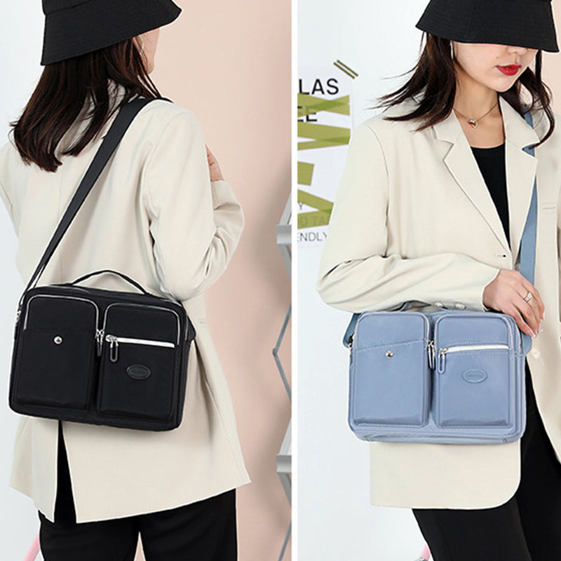 Due borse a tracolla da donna in tessuto, una nera e una grigia, indossate su giacca beige. Design elegante, tasche multiple, moda femminile.